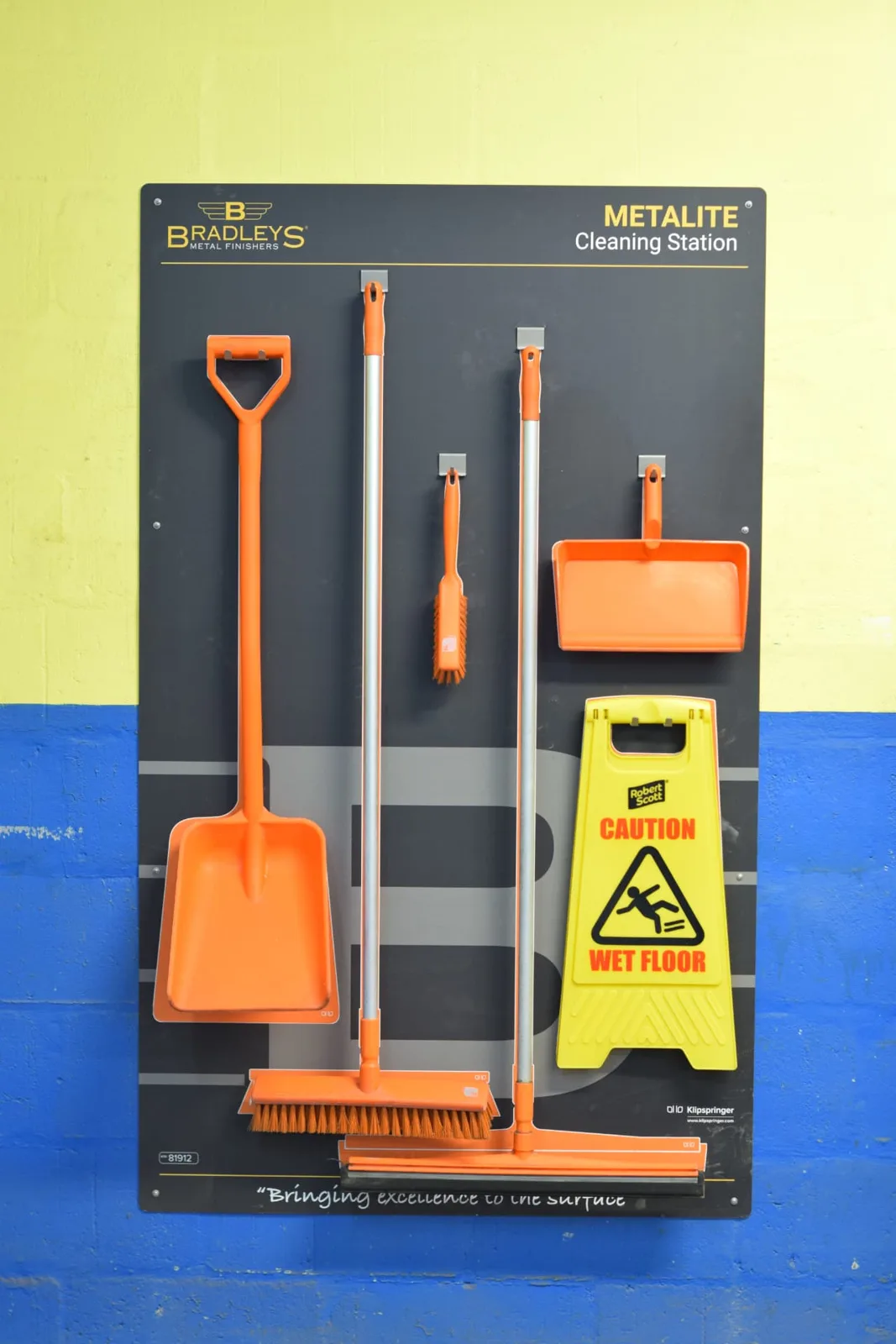Metalite cleaning station with orange equipment and a wet floor sign in shadowed positions