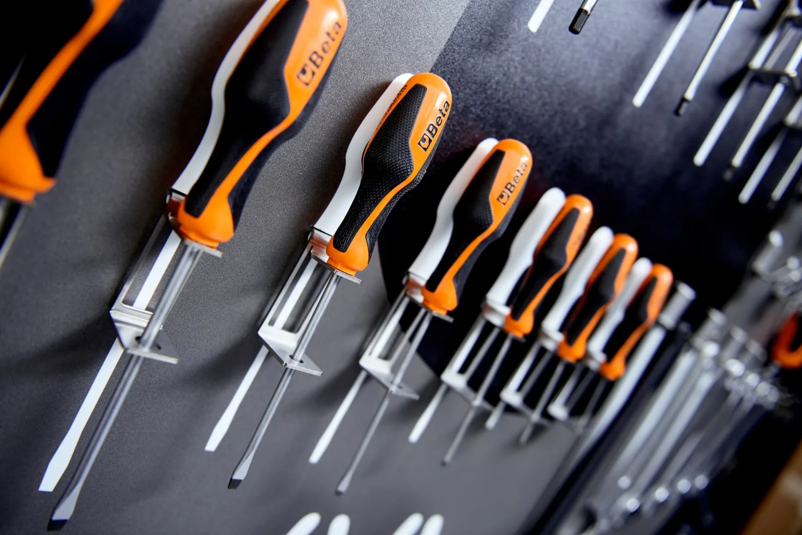 Close-up of screwdrivers held in stainless steel clips on a black shadow board