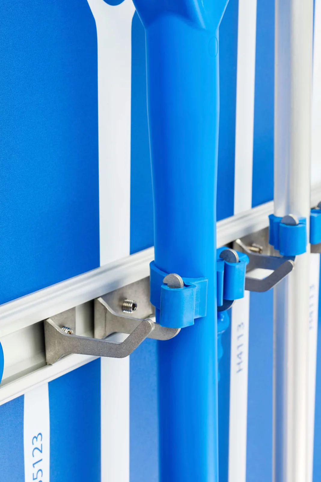 Close-up of blue handles held in clips on an aluminium extrusion rail